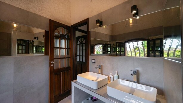 A modern bathroom with two sinks, a mirror, and a door leading to another room. - Villa Sicily Pool & Beach,  private pool a few steps from the beach and the sea (Fontane Bianche)
