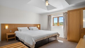 Un dormitorio con una cama grande, una mesita de noche, un armario y una ventana con cortinas.