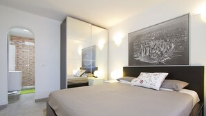 Une chambre d’hôtel moderne avec un grand lit, un miroir et une œuvre d’art accrochée au mur.