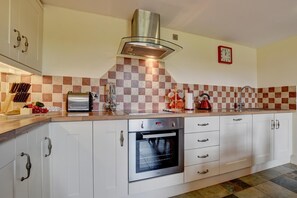 A modern kitchen with white cabinets, a stainless steel oven, and a checkered backsplash.