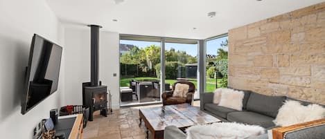 A modern living room with a fireplace, a flat-screen TV, and a stone wall.