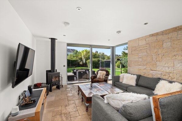 A modern living room with a fireplace, a flat-screen TV, and a stone wall.