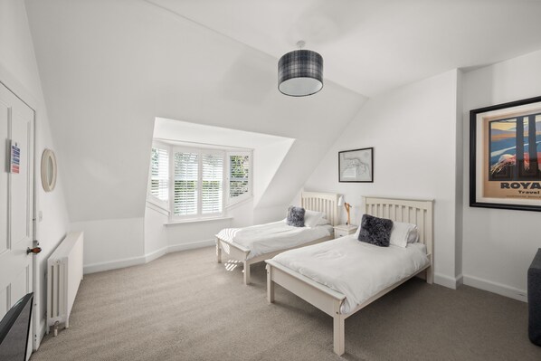 A bedroom with two single beds, a window with blinds, a radiator, and a framed picture on the wall. - Stylish 4‑Bedroom St Andrews Cottage with Private Garden, Parking & Walk to South Street (St. Andrews)