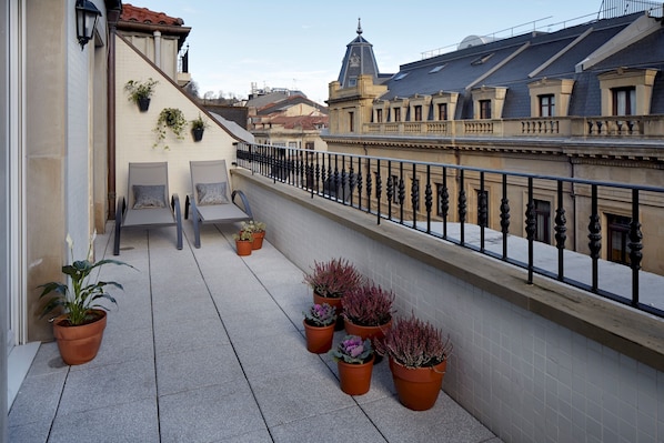 A balcony with potted plants, a seating area, and a view of surrounding buildings. - Garibay Terrace by FeelFree Rentals (San Sebastián)