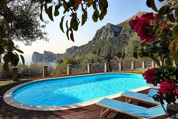 Una piscina con sillones de descanso y vistas a montañas.