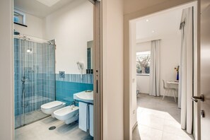Un baño moderno con cabina de ducha de vidrio, un lavamanos blanco y un bidé.