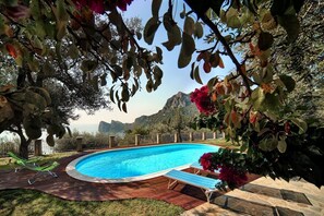 Una piscina con cubierta de madera, rodeada de vegetación y montañas al fondo.