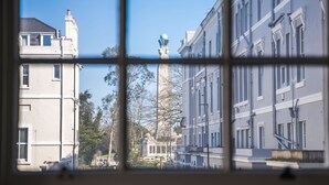 A view through a window with a grid pattern, featuring a tall building with a spherical structure on top, surrounded by other buildings with classical architecture. - RoomApart 1a stylish and modern studio apartment (Plymouth)