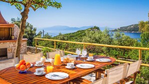 A breakfast table set outdoors with a scenic view of a lake and hills. - Villa Agapi - Four Bedroom Villa, Sleeps 8 (Lefkada)