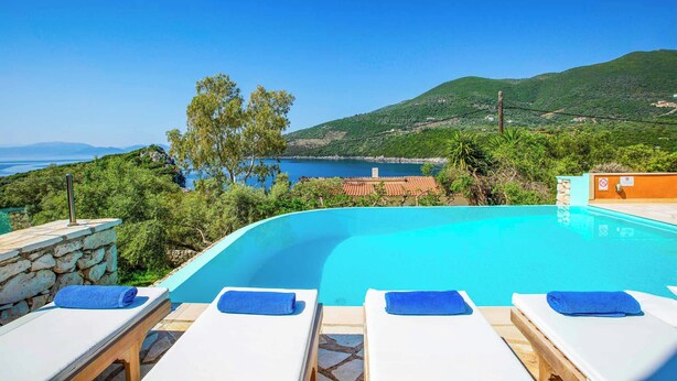 A clear blue swimming pool with lounge chairs and towels, surrounded by greenery and a view of the sea and hills. - Villa Agapi - Four Bedroom Villa, Sleeps 8 (Lefkada)