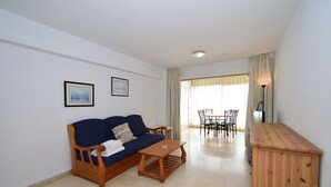 A living room with a sofa, coffee table, and a dining area with chairs and a table. - LOS CABALLOS (1 BEDROOM APARTMENT) (Benidorm)