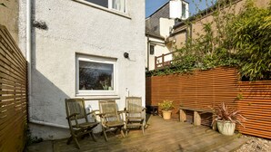 Eine Terrasse mit Holzstühlen, einem Fenster und einem Holzzaun.