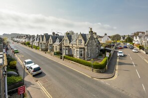 A residential street lined with traditional stone houses, a clear road, and a 'TO LET' sign.