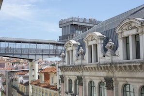 Een historisch gebouw met versierde architectuur, een brug op de achtergrond en uitzicht op de stad.