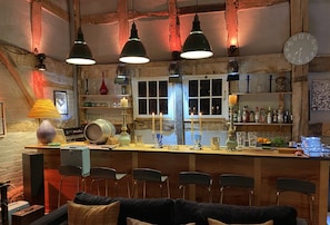 Een gezellige barruimte met houten balken, hanglampen en een bar met krukken.