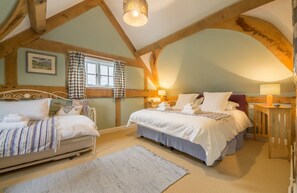 A bedroom with two beds, a window with checkered curtains, and a wooden ceiling.