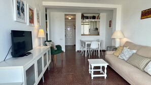 Un salon comprenant un téléviseur, un canapé, une table à manger et des chaises.