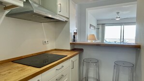 Une cuisine dotée d’un plan de travail en bois, de meubles blancs, d’une fenêtre offrant une belle vue et d’un ventilateur de plafond.