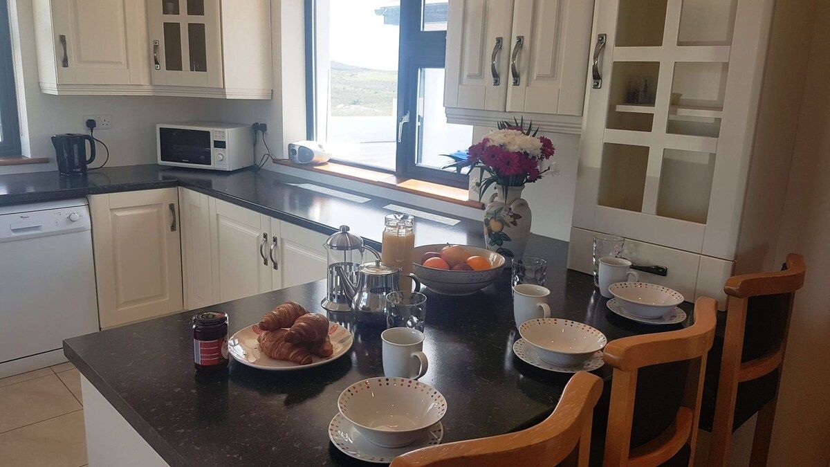 A kitchen with white cabinets, a microwave, a coffee maker, and a dining table set with plates, cups, and a vase with flowers.