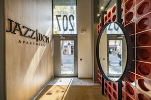 Un couloir avec un mur en bois, un miroir et une porte sur laquelle on peut apercevoir le mot « JAZZ ».