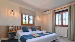 Une chambre bien éclairée, avec un grand lit, deux tables de chevet, une commode et une fenêtre avec des rideaux.
