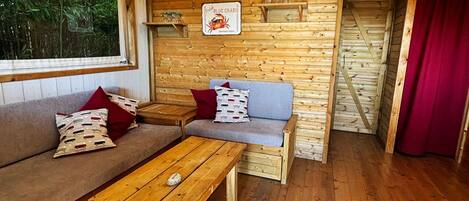 Interior acogedor de una cabaña con piso de madera, un sofá, una mesa y un letrero que indica que sirven cangrejos azules frescos.