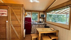 A compact kitchen with wooden walls, a red refrigerator, a wooden table with benches, and a window overlooking greenery. - A 2 bedroom luxury lodge with heated covered pool (Henansal)