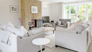A living room with two sofas, a coffee table, a TV, and a fireplace. - Old Lock Cottage, Birdham (Chichester)