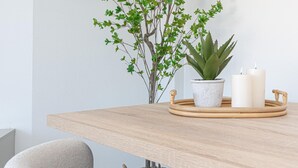 Une table en bois ornée d’une plante en pot, de bougies et d’un plateau en osier.
