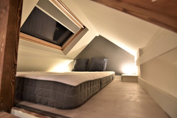 A small, sloped ceiling bedroom with a bed, a nightstand, and a window. - Attic House Zurenborg (Antwerpen)