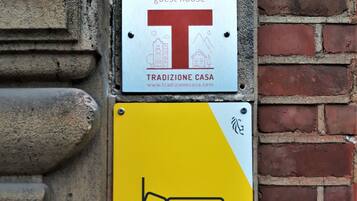 Due cartelli fissati a un muro in mattoni: uno è la targa di una pensione, Casa Zurenborg, e l'altro un simbolo di letto che indica la disponibilità di alloggi.