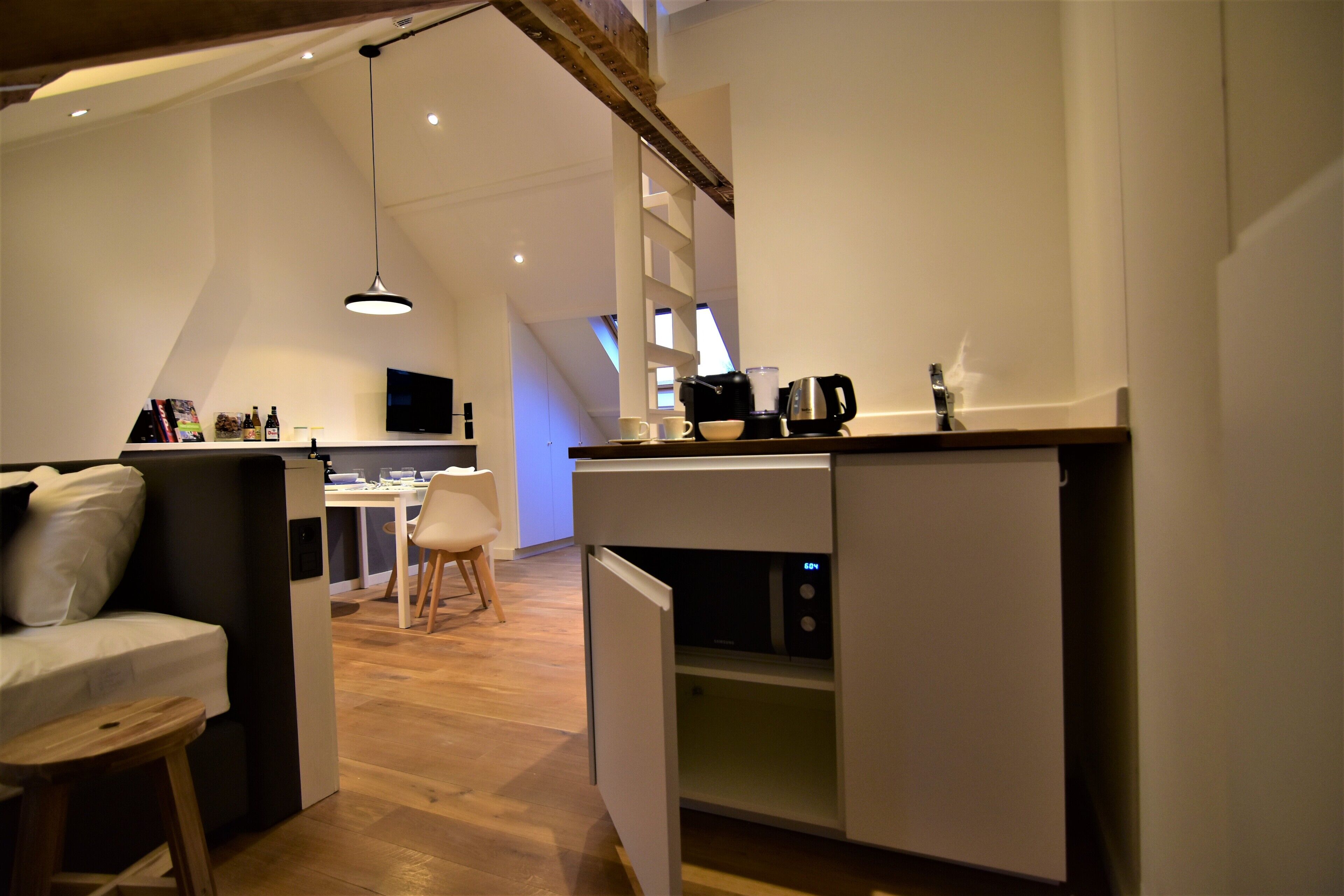 Eine moderne Küche mit Einbaukühlschrank, Kaffeemaschine und Mikrowelle. Es gibt einen Essbereich mit Tisch und Stühlen.