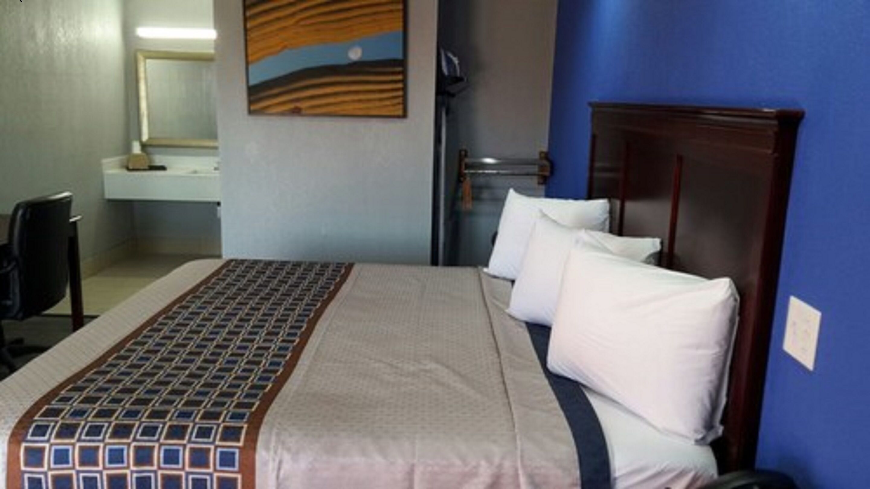 Una habitación de hotel con una cama, un escritorio y una silla.