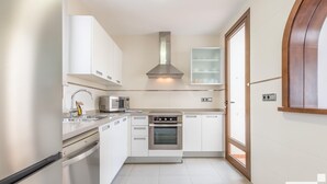 Una cocina moderna con armarios blancos, electrodomésticos de acero inoxidable y un horno empotrado.