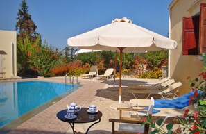 Una piscina con lettini e un tavolo con teiere.