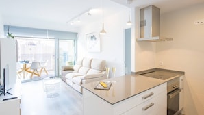 Een moderne keuken met een centraal eiland, een eethoek met een tafel en stoelen, en een bank.