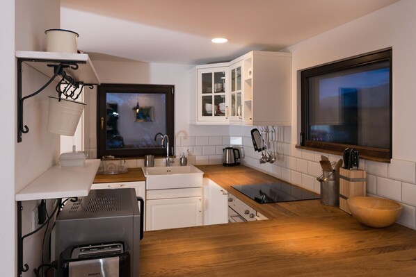 A modern kitchen with white cabinets, a wooden countertop, a built-in oven, and a window with a view.