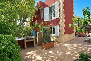 Ein rotes Gebäude mit einer Terrasse, Gartenmöbeln und einem Garten.