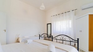 Un dormitorio con cama, mesita de noche, espejo y unidad de aire acondicionado.