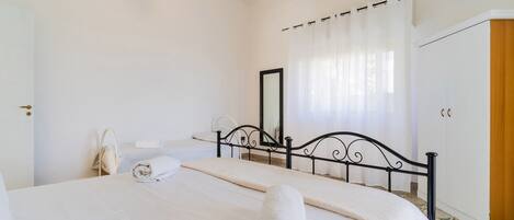 Ein Schlafzimmer mit Bett, Nachttisch, Spiegel und Klimaanlage.