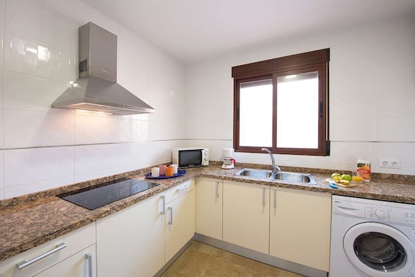 A compact kitchen with a microwave, sink, and built-in washing machine.