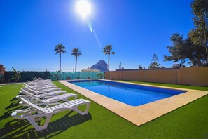 Piscina com cadeiras de descanso e vista para uma montanha.
