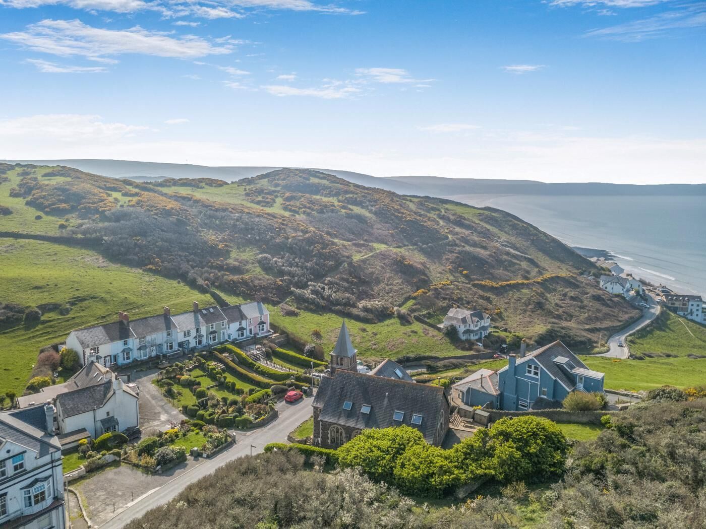 A coastal village with traditional houses, a church, and a road leading to the sea.