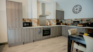 A modern kitchen with wooden cabinets, a built-in oven, a microwave, and a gas stove. - Lovely House with parking, garden, dogs welcome. Sleeps up to 7. Central Wirral (Heswall)