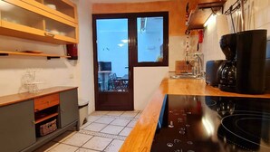 A kitchen with a black induction cooktop, wooden cabinets, and a view through a glass door. - CHARMING HOUSE IN THE HISTORIC CENTER OF TEGUISE (Teguise)