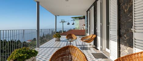 Un balcón con sillones de mimbre, una planta en maceta y vistas al mar.