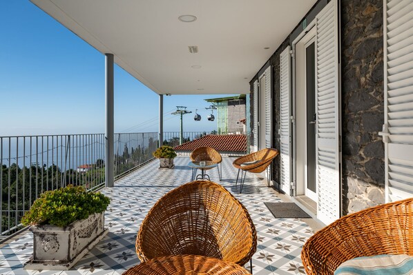Un balcón con sillones de mimbre, una planta en maceta y vistas al mar.