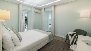 A hotel room with a bed, a desk, a chair, and a balcony with curtains. - 1-bed Superior Apt A2 in character Babosas Village (Funchal)