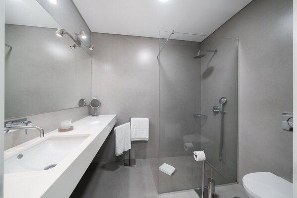 Un baño moderno con un espejo grande, dos lavamanos, una ducha y un inodoro.