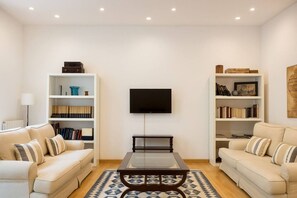 Un salon comprenant deux canapés, une table basse et deux étagères remplies de livres et d’objets décoratifs.